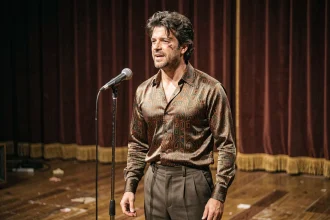 Chanteur français des années 80 en tenue de variété devant un rideau de studio télévision rétro